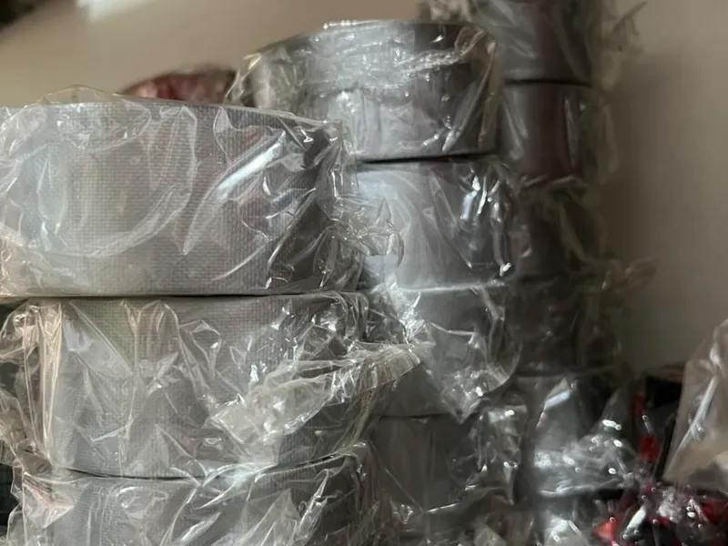 Tumpukan roll lakban kain warna abu-abu dalam kemasan
