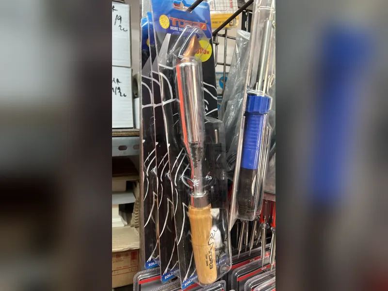 Solder listrik dengan gagang kayu tergantung di rak toko